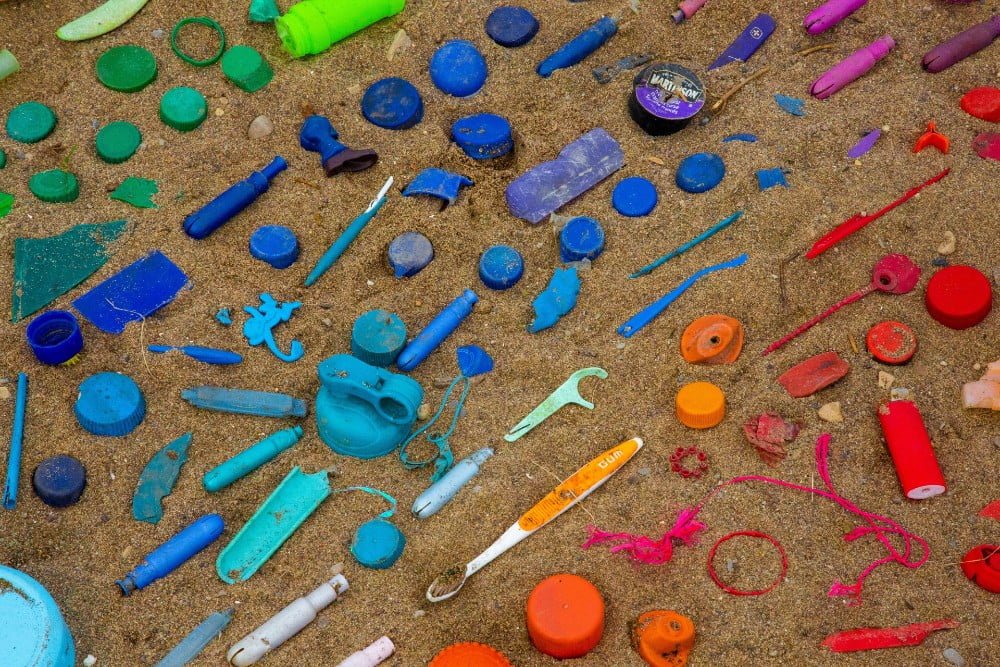 Color-coded plastic waste on a sandy beach